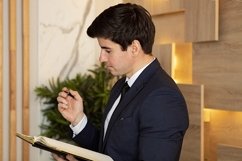 businessman in a dark blue suit writing in diary in office Product Image 1