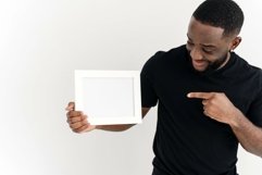 A black man points to a mockup in a white frame. Product Image 1