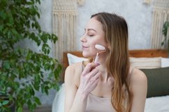 Young woman is doing Gua Sha facial massage in bathroom Product Image 1