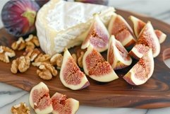 Sliced fig and brie cheese on wooden cutting board with waln Product Image 1