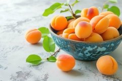 Fresh apricots in ceramic bowl on light surface Product Image 1