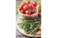 Uncooked asparagus with tomato on the wooden table Product Image 1