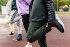 Close-up. Diverse people stretch their legs before running. Product Image 1