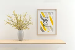 A closeup shot of a plant in a vase next to a frame Product Image 1