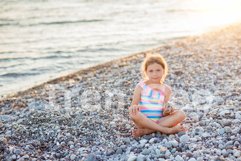Smiling child girl sits with a pyramid of stones in her hand Product Image 1