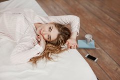 A beautiful young girl is lying on the bed and smiling Product Image 1