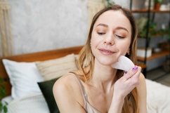 Young woman is doing Gua Sha facial massage in bathroom Product Image 1
