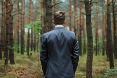 Businessman is standing in a forest looking at the trees Product Image 1