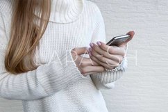 Woman in white sweater holding modern mobile phone Product Image 1