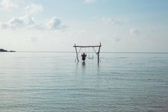 Lonely woman on wooden swing at sea shallow Product Image 1