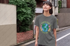 Digital PNG design featuring a hand-painted illustration of planet Earth with green continents and blue oceans, encircled by vibrant pink, orange, and purple flowers with leafy accents. The text &quot;Earth Day&quot; appears above and &quot;Go Planet!