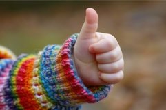 Baby wearing colorful knitted sleeve making thumbs up gestur Product Image 1