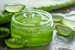 Jar of organic aloe vera gel surrounded by freshly cut aloe Product Image 1