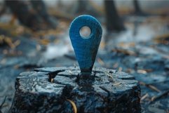 Blue wooden location pin standing on a wet stump in the fore Product Image 1