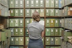 Woman contemplating files in archive room Product Image 1