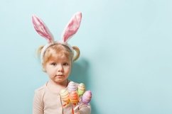 A little girl with bunny ears on her head holds easter eggs Product Image 1