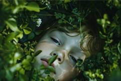 Closeup of a tranquil child&#039;s face peeking through lush leav Product Image 1
