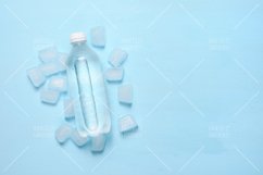Water bottle and ice pieces on blue table with text space Product Image 1