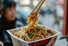 Chopsticks picking up noodles from take away box of chicken Product Image 1