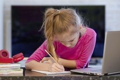 schoolgirl studying homework during her online lesson Product Image 1