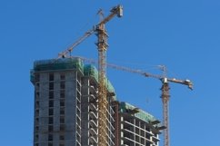 house under construction and cranes against the blue sky. Product Image 1