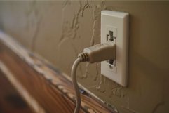White electrical power cord plugged into outlet on wall Product Image 1