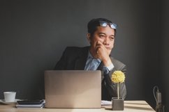 Businessman with hand raised on chin looking for idea Product Image 1