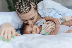 Modern caucasian woman kissing her baby while lying in bed Product Image 1