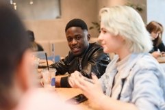 A black man meets with students in a cafe to chat. Product Image 1