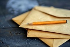 Classic pencil resting on stack of unopened envelopes on des Product Image 1