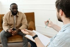 The therapist takes notes while talking to a depressed man Product Image 1