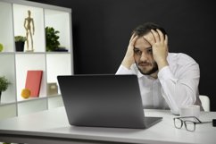 Depressed handsome freelancer sitting at desk in front Product Image 1