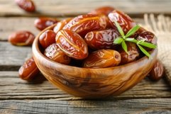 Fresh dates in wooden bowl with green leaves Product Image 1