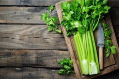 Fresh celery stalks lying on wooden cutting board Product Image 1