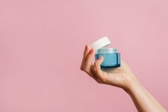Female hand holding blue jar of cosmetic cream on pink Product Image 1