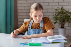 A girl does homework with a book at home Product Image 1