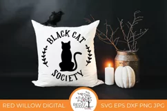 Simple black cat design on a white throw pillow on a black background.