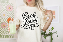 Reader themed calligraphy SVG that says Book Lover with ornamental swirl lines, displayed on a white plank background for digital download listing.