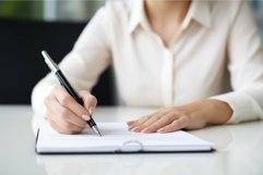 Hands of adult woman with pen and glasses on desktop. Genera Product Image 1