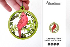 A beautiful Christmas ornament with cardinal and branches behind it.