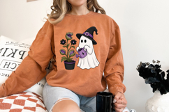 Halloween sublimation design with a ghost in a witch hat watering a creepy cute monster plant growing in a black flower pot.