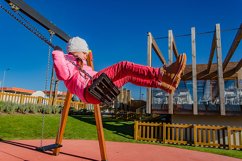 Little girl 5-6 years on a playground swinging on swing. Product Image 1