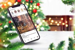 Christmas iPhone 13 mockup on marble table with a christmas tree and Christmas decorations in the background