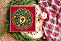 A playful holiday craft PNG showing a dog's black nose, shaggy tan fur, and little pink tongue nestled among dense green evergreen branches and festive lights.