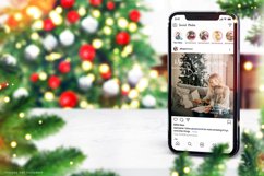 Christmas iPhone 13 mockup on marble table with a christmas tree and Christmas decorations in the background