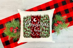 christmas sublimation design on a red and green background with a phrase Christmas is here on a white pillow