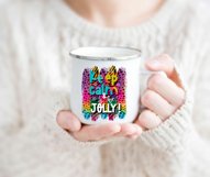 Christmas sublimation design with a phrase saying keep calm and be jolly on a colorful bright background on a white cup held by a woman