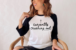 Faith-based typography graphic with a small cross icon above the words “Currently Crashing Out But Still Chosen” in modern script lettering, suitable for creating Christian apparel and handmade gifts.