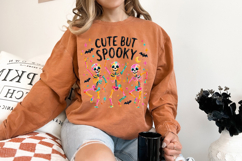 Cute spooky PNG design with three bright skeletons dancing together, surrounded by bats, stars, moon accents, and colorful confetti-style marks.