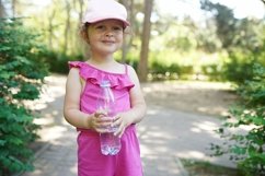 Child girl in pink cap holding mineral water bottle Product Image 1
